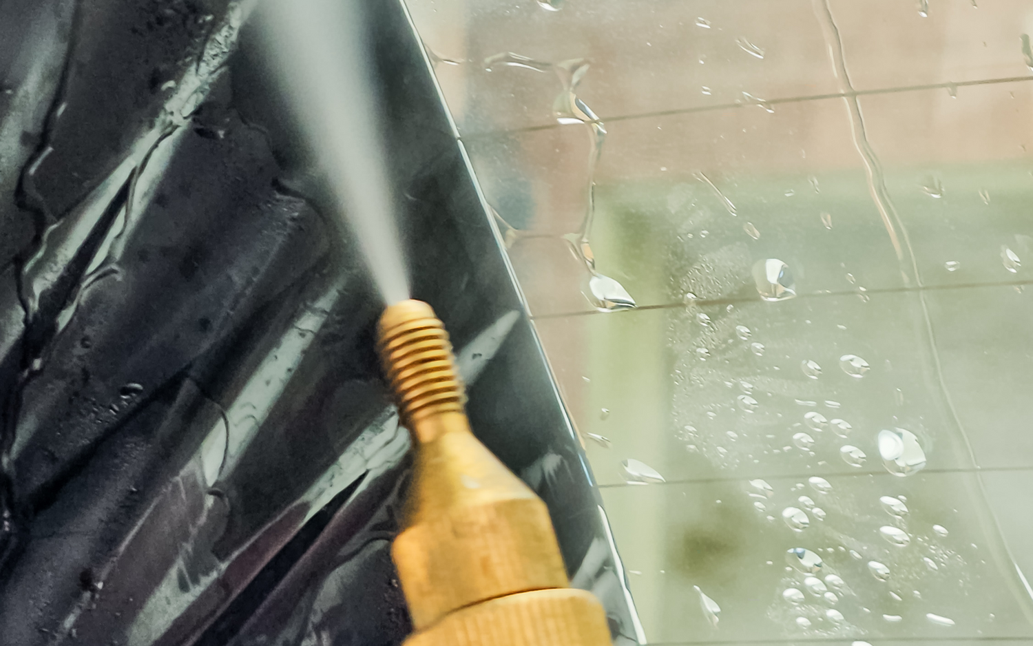 A steamer emitting steady streams of hot vapor, effectively softening the adhesive for easy window tint removal. This image serves as a practical visual guide on how to remove window tinting efficiently.