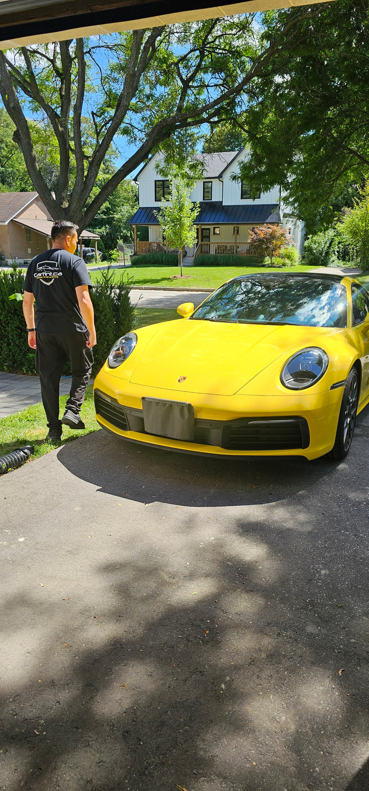 A bright yellow Porsche parked outside on a sunny day with newly tinted dark windows, illustrating our expert mobile car window tinting service where our Toronto technicians come directly to your house for a clean, factory finish installation