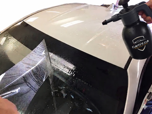 Close-up of our expert car window tinting process, showing a windshield sun strip being carefully installed to block blinding sun glare and harmful UV rays.